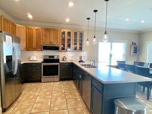 A modern kitchen with wooden cabinets, stainless steel appliances, and a large island.