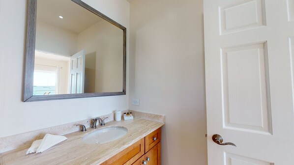 Un baño con lavamanos doble, un espejo grande y armarios de madera.