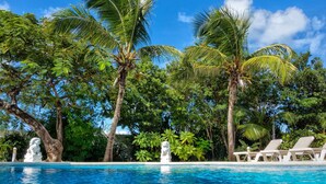 A swimming pool surrounded by palm trees and lush greenery.