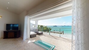 A balcony with a view of the sea, a television, and a seating area.