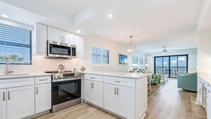 A modern kitchen with white cabinetry, stainless steel appliances, and a large island. - OCEAN'S REACH 1D2: 2-Bedroom, Corner Unit, Dunes Golf Privileges! (Sanibel Island)