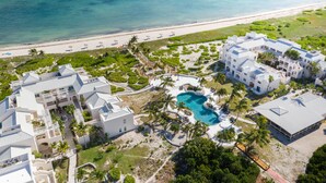 An aerial view of a resort with multiple buildings, a swimming pool, and a beach.