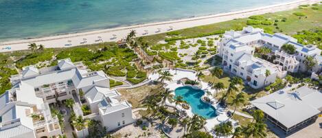 An aerial view of a resort with multiple buildings, a swimming pool, and a beach.