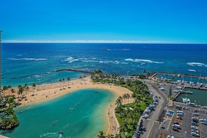 A coastal area with a beach, a parking lot, and a marina.