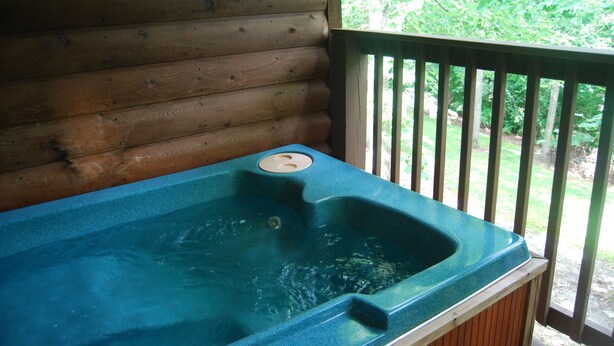 A wooden cabin with a hot tub on a deck.