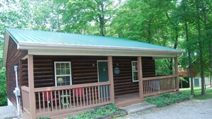A log cabin with a porch, a green door, and a sign that reads "Cottage".