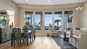 A spacious living room with a dining area, large windows offering a view of the ocean, and modern lighting fixtures. - CAMELBACK MT BEAUTY PARADISE VALLEY SCOTTSDALE AREA (Paradise Valley)