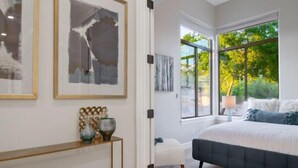 A bedroom with a large bed, a console table with decorative items, and framed artwork on the wall. - CAMELBACK MT BEAUTY PARADISE VALLEY SCOTTSDALE AREA (Paradise Valley)