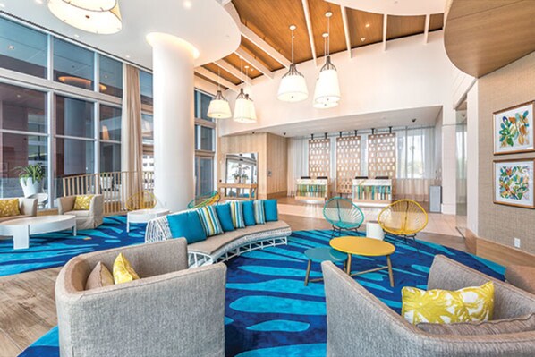 A spacious lobby with a blue patterned carpet, modern furniture, and large windows.