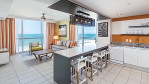 A modern kitchen with a central island, bar stools, and a view of the ocean.