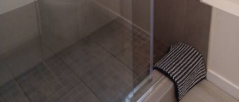 A modern bathroom with a glass shower enclosure, a toilet, and a shelf with toiletries.