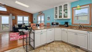 A spacious living area with a wooden ceiling, a kitchen with white cabinets and granite countertops, and a balcony with a view. - Beachfront Home- Amazing Oceanfront w/ Hot tub!!! Sleeps 8- Free Wifi! -6 beds (Kill Devil Hills)