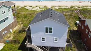 A beachfront property with a two-story house, a wooden deck, and a view of the beach. - Beachfront Home- Amazing Oceanfront w/ Hot tub!!! Sleeps 8- Free Wifi! -6 beds (Kill Devil Hills)