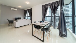 A modern living room with a white sofa, a dining table with chairs, and a TV. - OYO Home 44045 Splendid 2br Arte Plus (Kuala Lumpur)