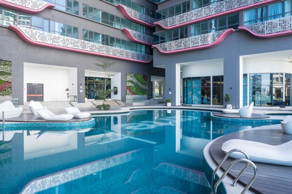 Relax by the large indoor pool surrounded by comfortable lounge chairs and a wooden deck.
