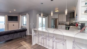 Une cuisine moderne dotée d’un îlot central, de tabourets de bar et offrant une vue sur la mer.