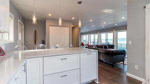 Une cuisine moderne avec des meubles blancs, un plan de travail en marbre et des luminaires suspendus.