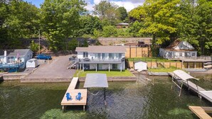 Une propriété au bord du lac, comprenant un quai, une petite maison et un bâtiment plus grand doté d’un balcon.