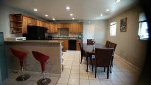 A modern kitchen with wooden cabinets, a black refrigerator, and a dining area with a table and chairs.