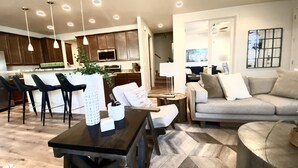A modern living room with a sofa, chairs, a coffee table, and a dining area with a kitchen in the background. - Stunning New Contemporary Home Minutes to Downtown Flagstaff (Flagstaff)