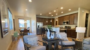 A spacious living room with a large sofa, a coffee table, and a dining area with a table and chairs. - Stunning New Contemporary Home Minutes to Downtown Flagstaff (Flagstaff)