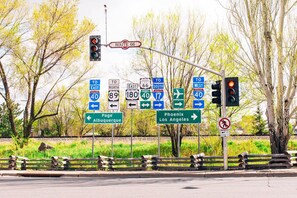 A traffic intersection with multiple directional signs, a pedestrian crossing signal, and a wooden fence. - Stunning New Contemporary Home Minutes to Downtown Flagstaff (Flagstaff)