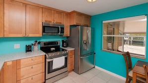 A kitchen with wooden cabinets, stainless steel appliances, a window, and a view of the outside. - Waterfront Marathon FL Keys Home w/ Private Dock (Marathon)