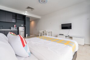 A hotel room with a bed, a desk, a TV, and a kitchenette. - OYO Home 43951 Fair  Studio Empire City Marriot (Petaling Jaya)