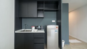 A compact kitchen with a built-in microwave, a stainless steel refrigerator, and a sink with a faucet. - OYO Home 43951 Fair  Studio Empire City Marriot (Petaling Jaya)