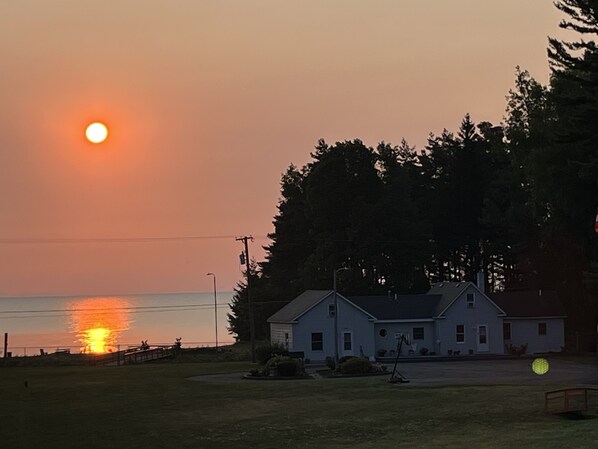 A house with a front yard and a body of water in the background. - Sunrise in Sandy Beach Property 1 (Harbor Beach)