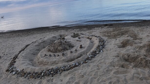 Een zandstrand met een cirkelvormige stenen opstelling.