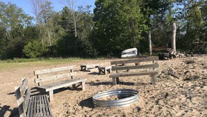 Een zandstrand met houten banken en een metalen prullenbak.