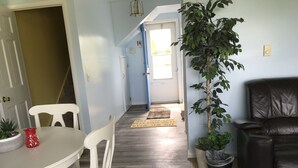 Een eethoek met een witte tafel en stoelen, een plant in pot en een leren bank.