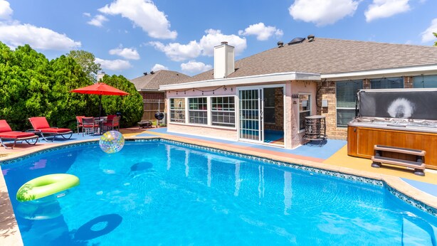 Ein Garten mit Schwimmbad, roten Liegestühlen, einem Whirlpool und einer Grillgegend.