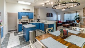 Eine moderne Küche mit blauen Schränken, einer zentralen Kochinsel und einem Essbereich mit Holztisch und Stühlen.