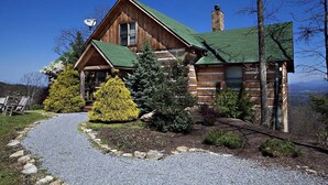 A log cabin with a green roof, surrounded by a gravel path and various shrubs. - Top-of-Mountain Cabin w/ Views, Hot Tub & Game Room – Near Pigeon Forge (Sevierville)