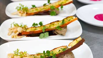 A row of white plates with food, each garnished with green herbs.