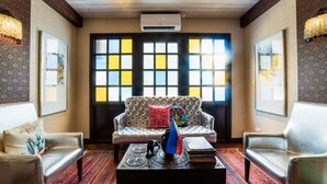 A room with a tufted sofa, two armchairs, a patterned rug, and a decorative table with books and a vase. - Gwandalan House (Dipolog)