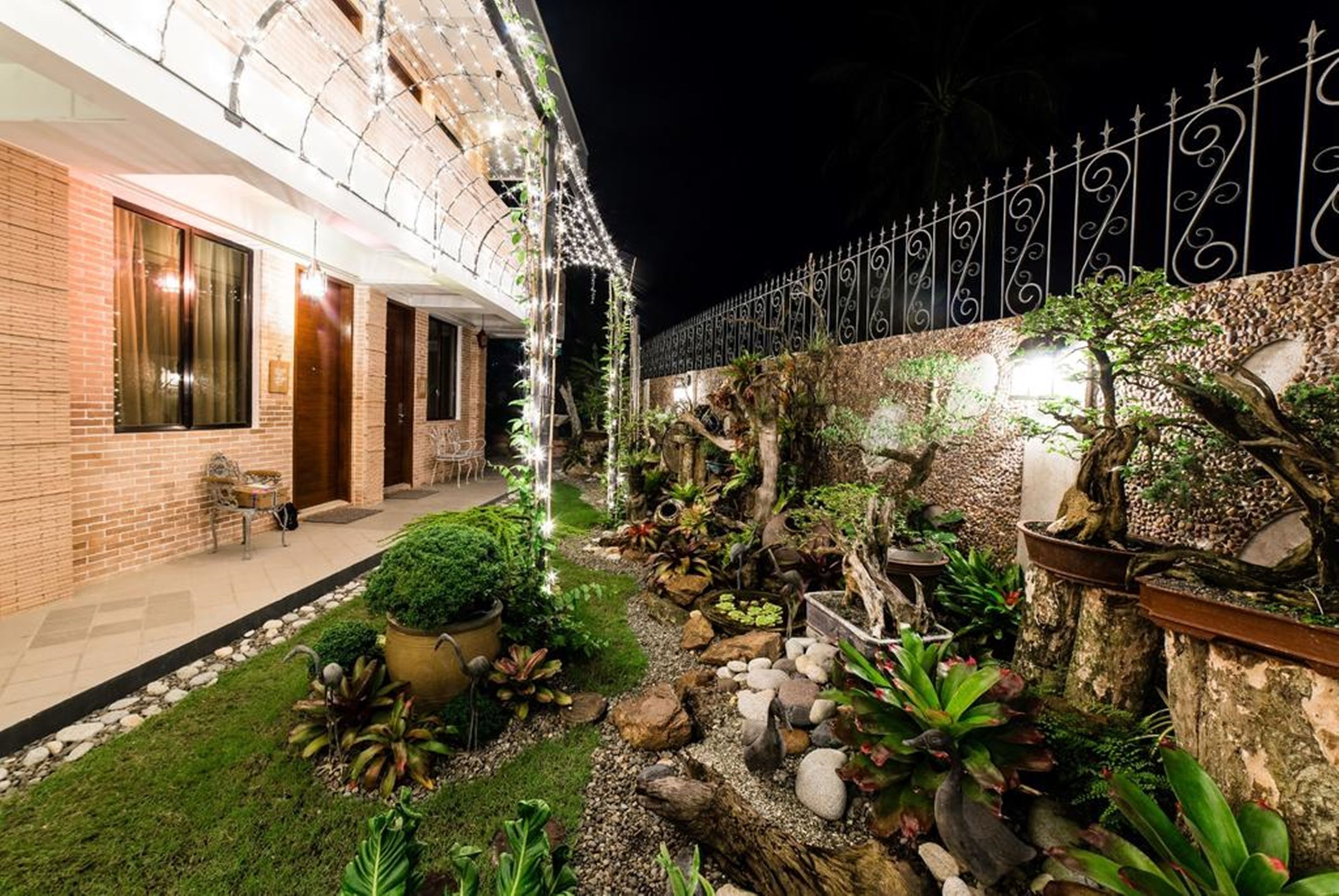 Un espace extérieur aménagé en jardin, bien éclairé, avec une variété de plantes, et un bâtiment en briques doté de grandes fenêtres.