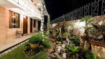 Un espace extérieur aménagé en jardin, bien éclairé, avec une variété de plantes, et un bâtiment en briques doté de grandes fenêtres.