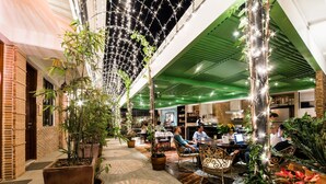An indoor dining area with brick walls, green ceiling, and string lights. Tables and chairs are arranged for dining. - Gwandalan House (Dipolog)