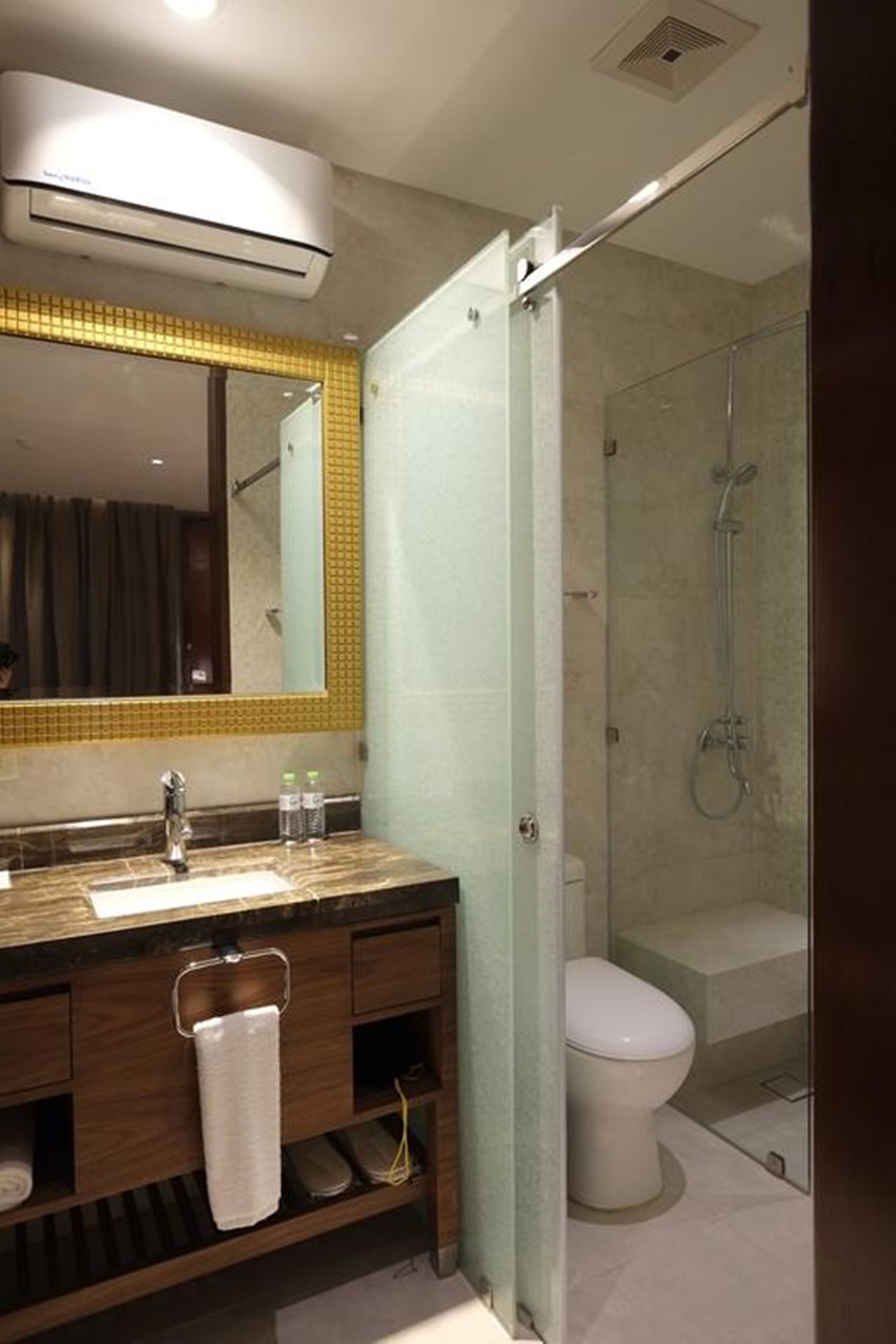 A bathroom with a wooden vanity, a mirror, a shower, and a toilet.