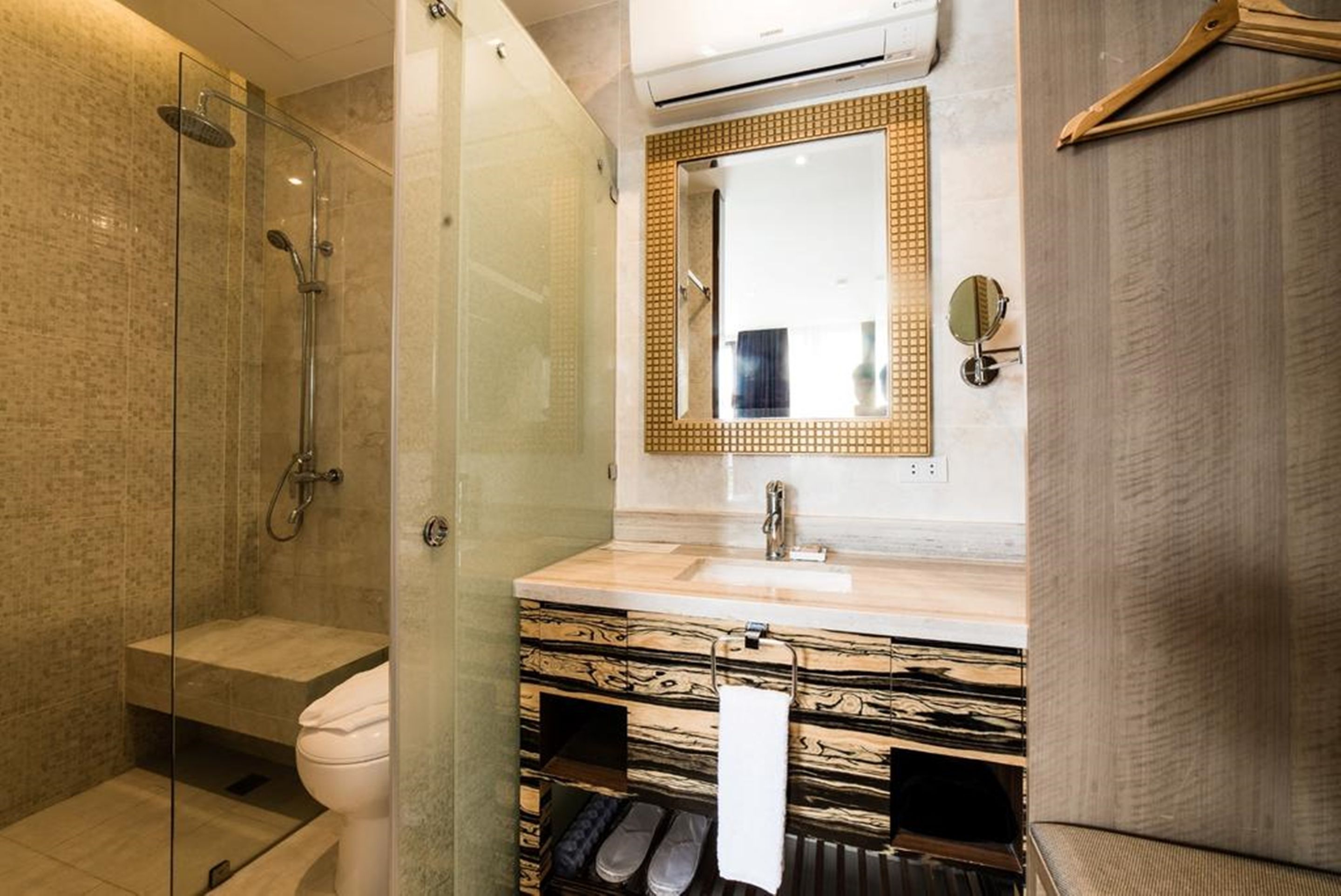 A modern bathroom with a glass-enclosed shower, a marble vanity, and a large mirror.