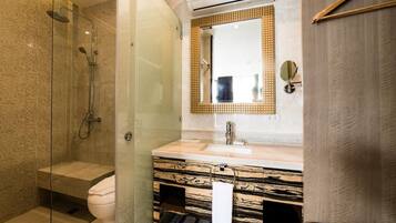 Un baño moderno con ducha de vidrio, tocador de mármol y un espejo grande.