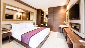 A modern hotel room with a large bed, a bedside table, a mirror, a TV, and a wooden wardrobe. - Gwandalan House (Dipolog)