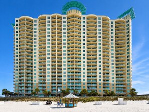 A multi-story hotel with balconies, a beachside location, and a beachside kiosk.