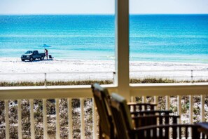 A beach view from a porch with a chair and a truck on the sand. - Semper Fi Grayton gulf front 3bedroom, 3 bath On Gulf (Santa Rosa Beach)