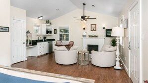 A spacious living area with a fireplace, a dining table, and two armchairs.