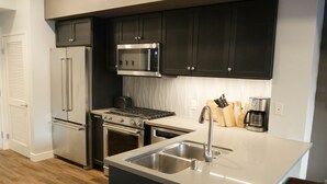 A modern kitchen with dark cabinets, stainless steel appliances, and a central island with a sink.