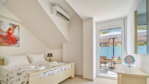 A bedroom with a bed, bedside table, and a window with a view of the outside. - Villa by the Lake with 2 Newly Built Private Pool (Georgioupolis)
